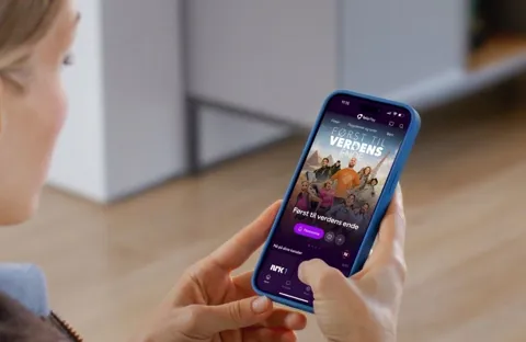 Så mye sparer du med ekstra poengene fra Telia Play Illustrasjonsbilde av en lyshåret kvinne som sitter med en mobil i hendene og ser på Telia Play-appen.